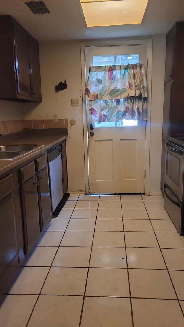 kitchen featuring sink, stove, stainless steel dishwasher, and light tile flooring