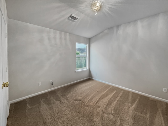 empty room featuring dark colored carpet and lofted ceiling