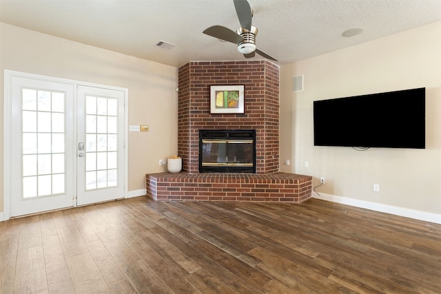 unfurnished living room with wood-type flooring, french doors, and a brick fireplace