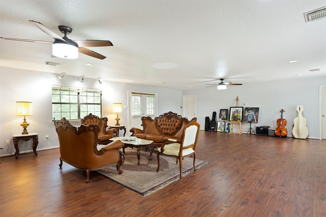 living room featuring a textured ceiling, ceiling fan, and dark wood-type flooring