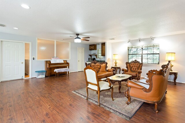 living room featuring a textured ceiling, ceiling fan, and dark wood-type flooring