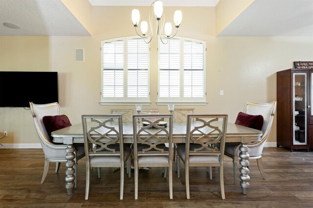 dining area with a textured ceiling, dark hardwood / wood-style flooring, and an inviting chandelier