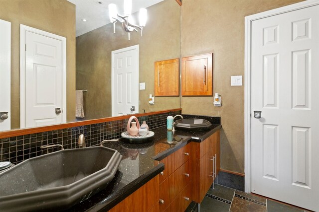 bathroom with tasteful backsplash, tile floors, vanity with extensive cabinet space, and double sink