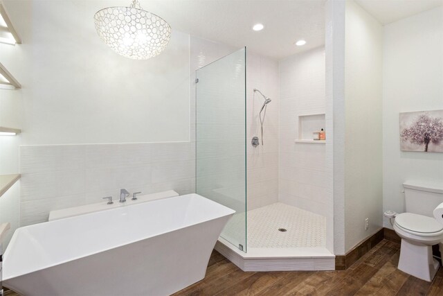 bathroom with wood-type flooring, independent shower and bath, tile walls, and toilet