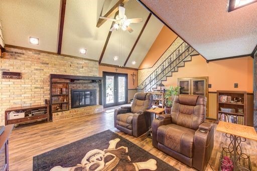 living room with brick wall, wood-type flooring, a textured ceiling, and a fireplace