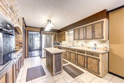 kitchen with backsplash, stainless steel appliances, light tile floors, and a kitchen island