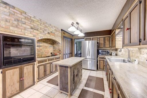 kitchen featuring sink, tasteful backsplash, light tile floors, and black appliances