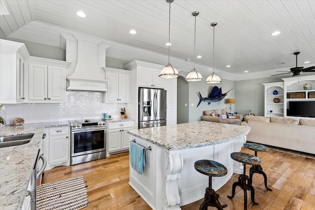 kitchen with premium range hood, stainless steel appliances, tasteful backsplash, white cabinetry, and light wood-type flooring