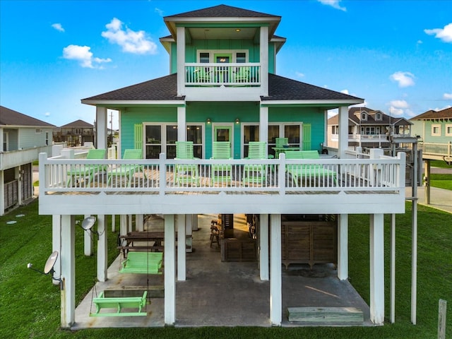 rear view of house featuring a wooden deck, a balcony, and a yard