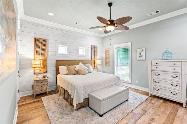 bedroom featuring wooden walls, crown molding, light hardwood / wood-style flooring, and ceiling fan