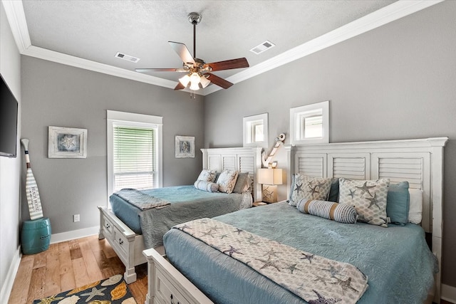 bedroom featuring ornamental molding, ceiling fan, a textured ceiling, and light wood-type flooring