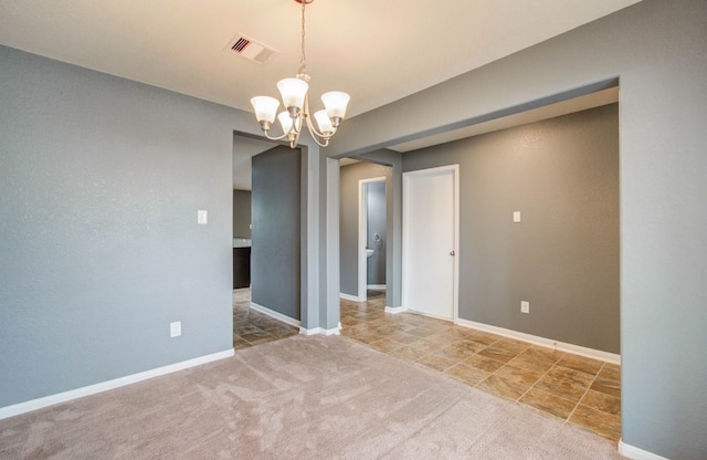 carpeted empty room featuring a chandelier