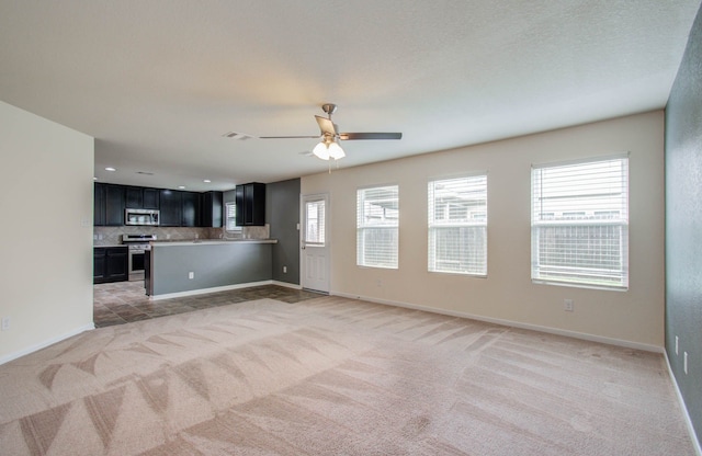 unfurnished living room with plenty of natural light, ceiling fan, and light carpet