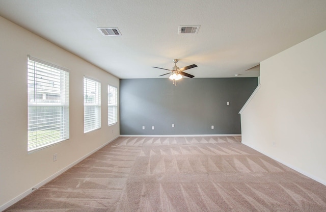 unfurnished room with plenty of natural light, ceiling fan, and light colored carpet