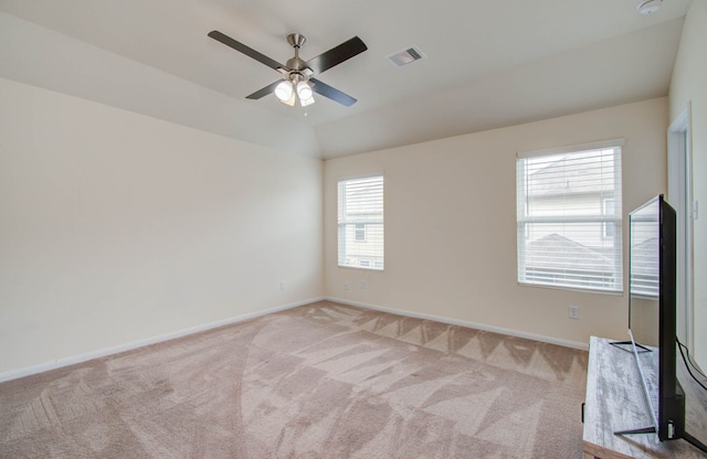 empty room with plenty of natural light, ceiling fan, and carpet