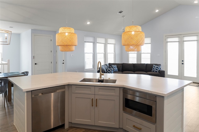 kitchen with appliances with stainless steel finishes, a center island with sink, decorative light fixtures, and sink