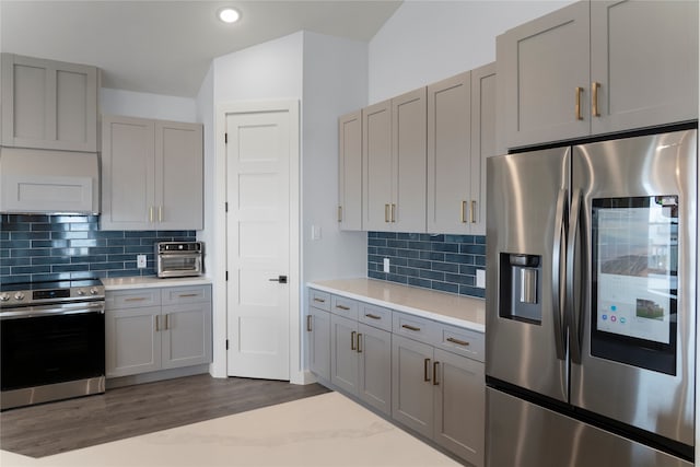 kitchen featuring decorative backsplash, dark hardwood / wood-style floors, stainless steel appliances, gray cabinetry, and extractor fan