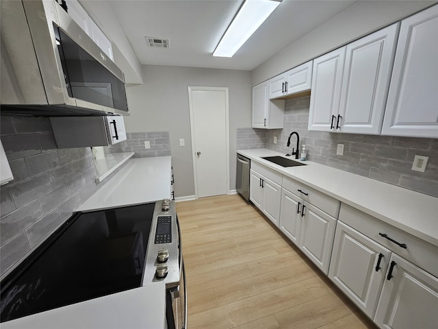 kitchen featuring white cabinets, stainless steel appliances, light hardwood / wood-style floors, and sink