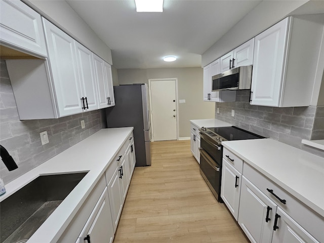 kitchen with tasteful backsplash, white cabinetry, sink, and stainless steel appliances