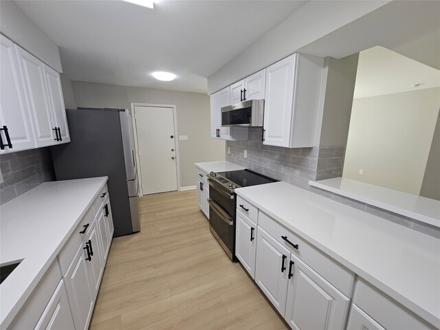 kitchen featuring tasteful backsplash, white cabinets, stainless steel appliances, and light wood-type flooring