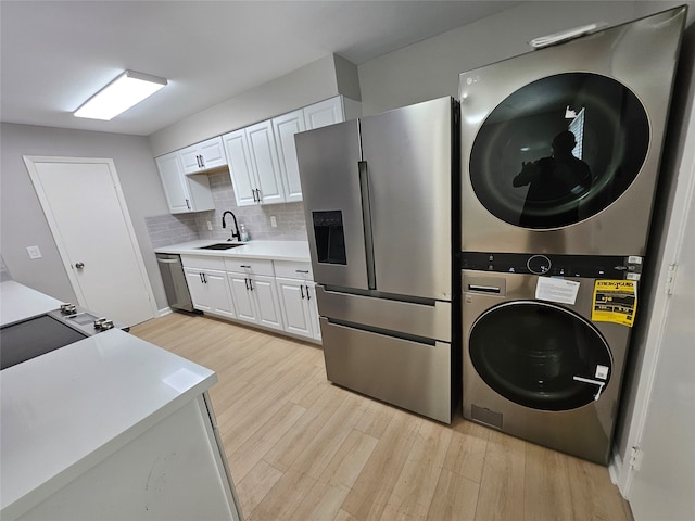 laundry area featuring stacked washer / drying machine, light hardwood / wood-style floors, and sink