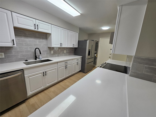 kitchen featuring decorative backsplash, stainless steel appliances, sink, white cabinets, and light hardwood / wood-style floors