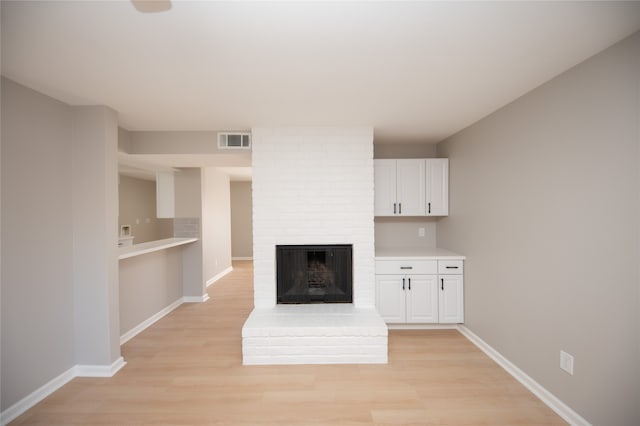 unfurnished living room with light hardwood / wood-style floors and a brick fireplace