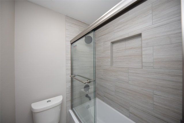 bathroom with combined bath / shower with glass door and toilet