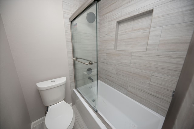 bathroom featuring toilet and bath / shower combo with glass door