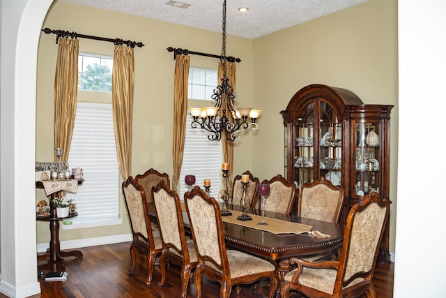 dining room with dark wood-type flooring, a notable chandelier, and a textured ceiling