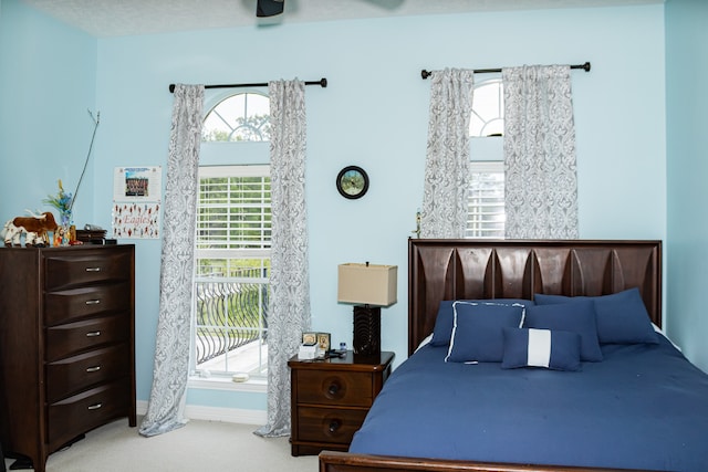 carpeted bedroom with ceiling fan and a textured ceiling