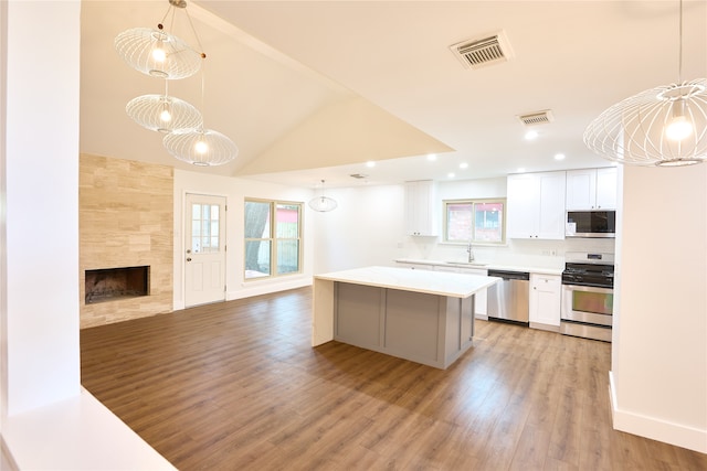 kitchen with white cabinetry, appliances with stainless steel finishes, decorative light fixtures, and light wood-type flooring