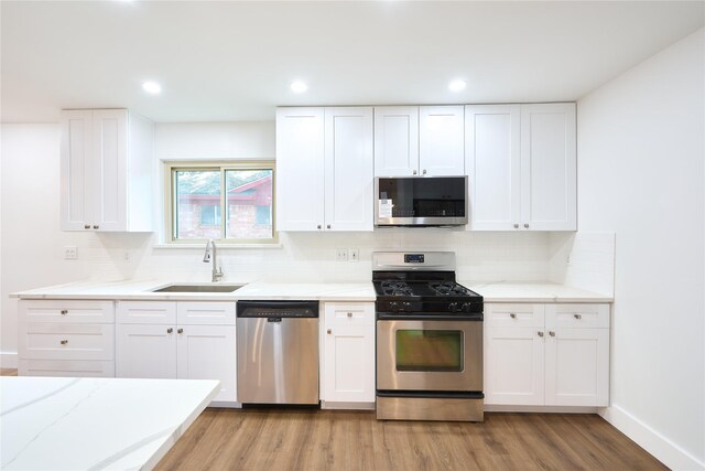 15830 Whipple Tree Dr, Houston, TX 77070 - kitchen featuring appliances with stainless steel finishes, a sink, light wood finished floors, tasteful backsplash, and white cabinets