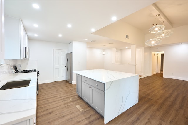 kitchen with appliances with stainless steel finishes, light stone counters, pendant lighting, white cabinets, and dark wood-type flooring