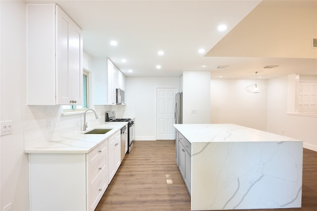 kitchen featuring stainless steel appliances, pendant lighting, light stone countertops, white cabinetry, and light wood-type flooring