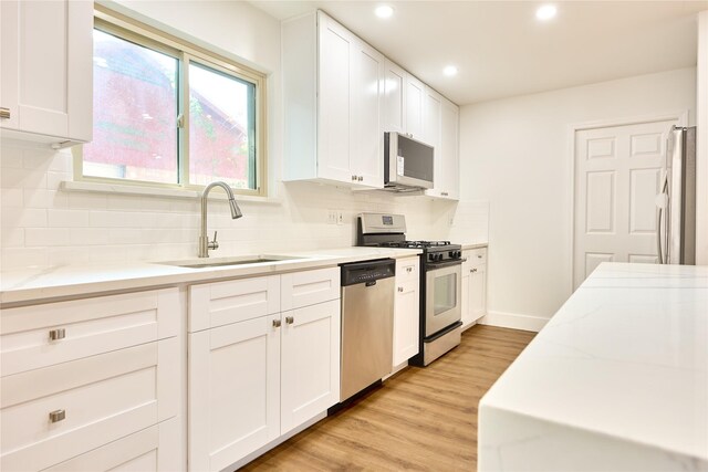 15830 Whipple Tree Dr, Houston, TX 77070 - kitchen with appliances with stainless steel finishes, a sink, recessed lighting, white cabinets, and light wood-type flooring