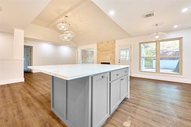 kitchen with pendant lighting, gray cabinets, a kitchen island, and vaulted ceiling