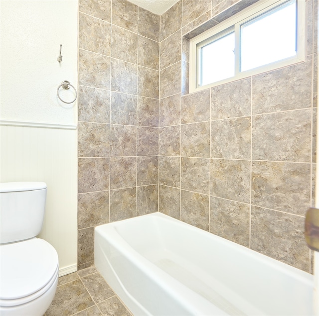 bathroom with toilet, tiled shower / bath combo, and tile patterned flooring