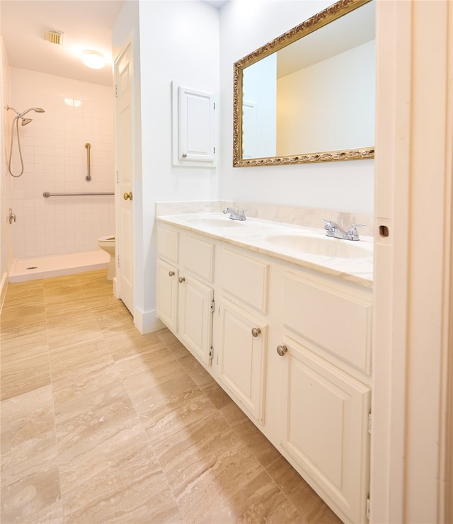 bathroom with vanity, toilet, and tiled shower