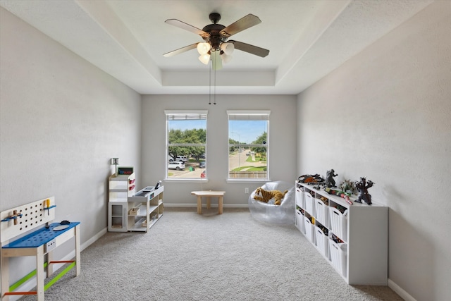 rec room with light colored carpet, ceiling fan, and a tray ceiling