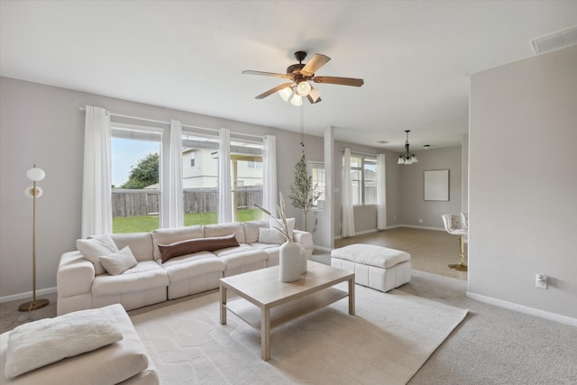 carpeted living room featuring ceiling fan with notable chandelier