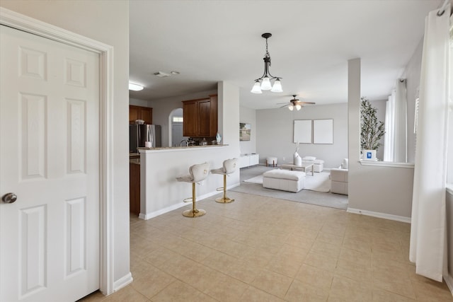 interior space with ceiling fan, stainless steel fridge, light tile floors, and pendant lighting