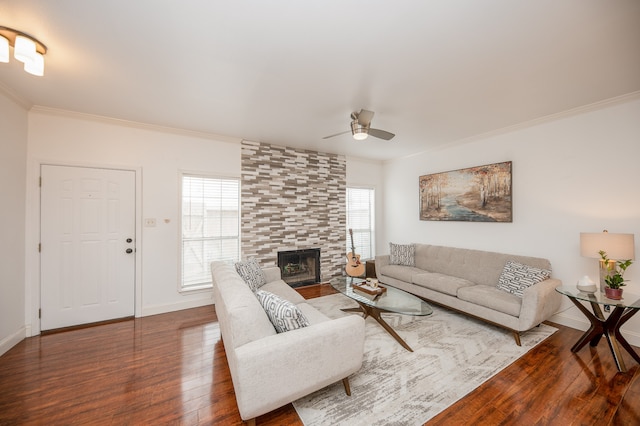 living room featuring hardwood / wood-style flooring, ceiling fan, crown molding, and a tiled fireplace