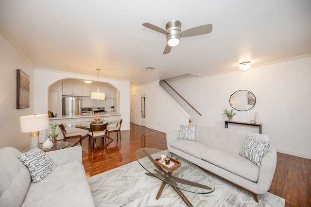 living room with ceiling fan, wood-type flooring, and ornamental molding