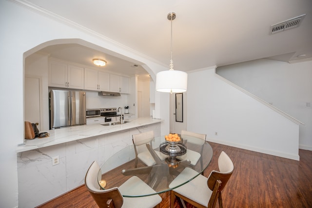 dining area with sink, dark hardwood / wood-style floors, and ornamental molding