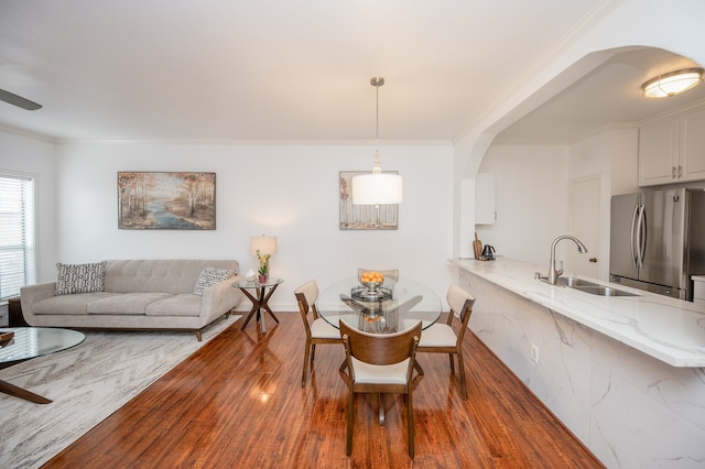 dining space featuring dark hardwood / wood-style flooring, ornamental molding, and sink