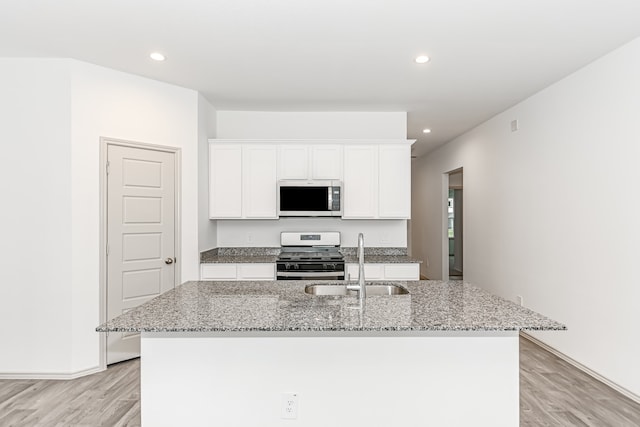 kitchen with appliances with stainless steel finishes, light hardwood / wood-style flooring, sink, and a center island with sink