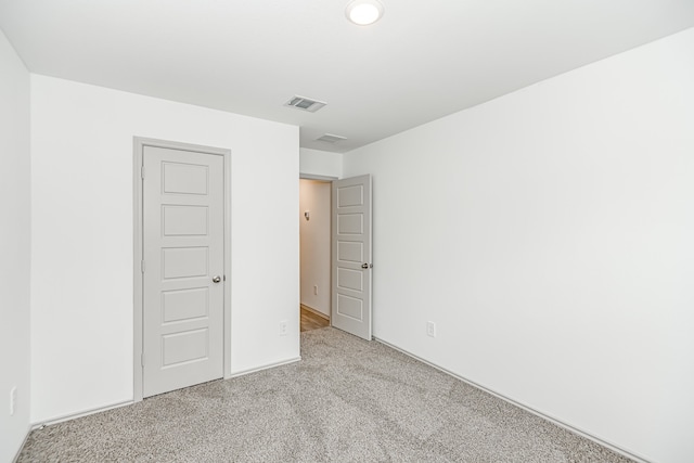 unfurnished bedroom featuring light colored carpet and a closet