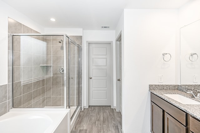 bathroom with wood-type flooring, separate shower and tub, and large vanity