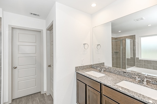 bathroom with dual sinks, wood-type flooring, oversized vanity, and a bathing tub